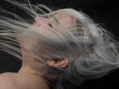 a woman with grey hair blowing in the wind