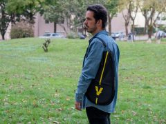 A man standing in a field with a backpack on his back